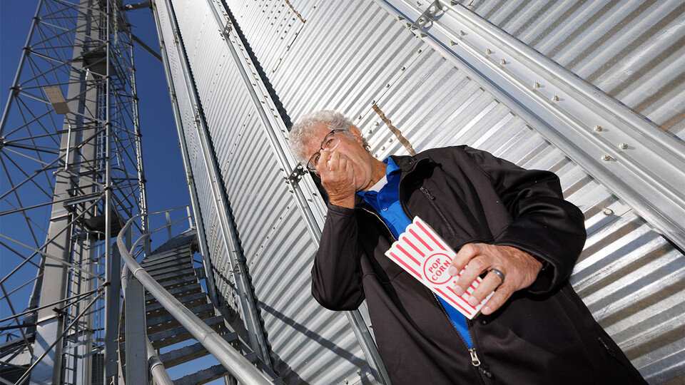 Husker alumnus Norm Krug enjoys a handful of Preferred Popcorn standing at the base of a grain bin on his Chapman, Nebraska, farm. 