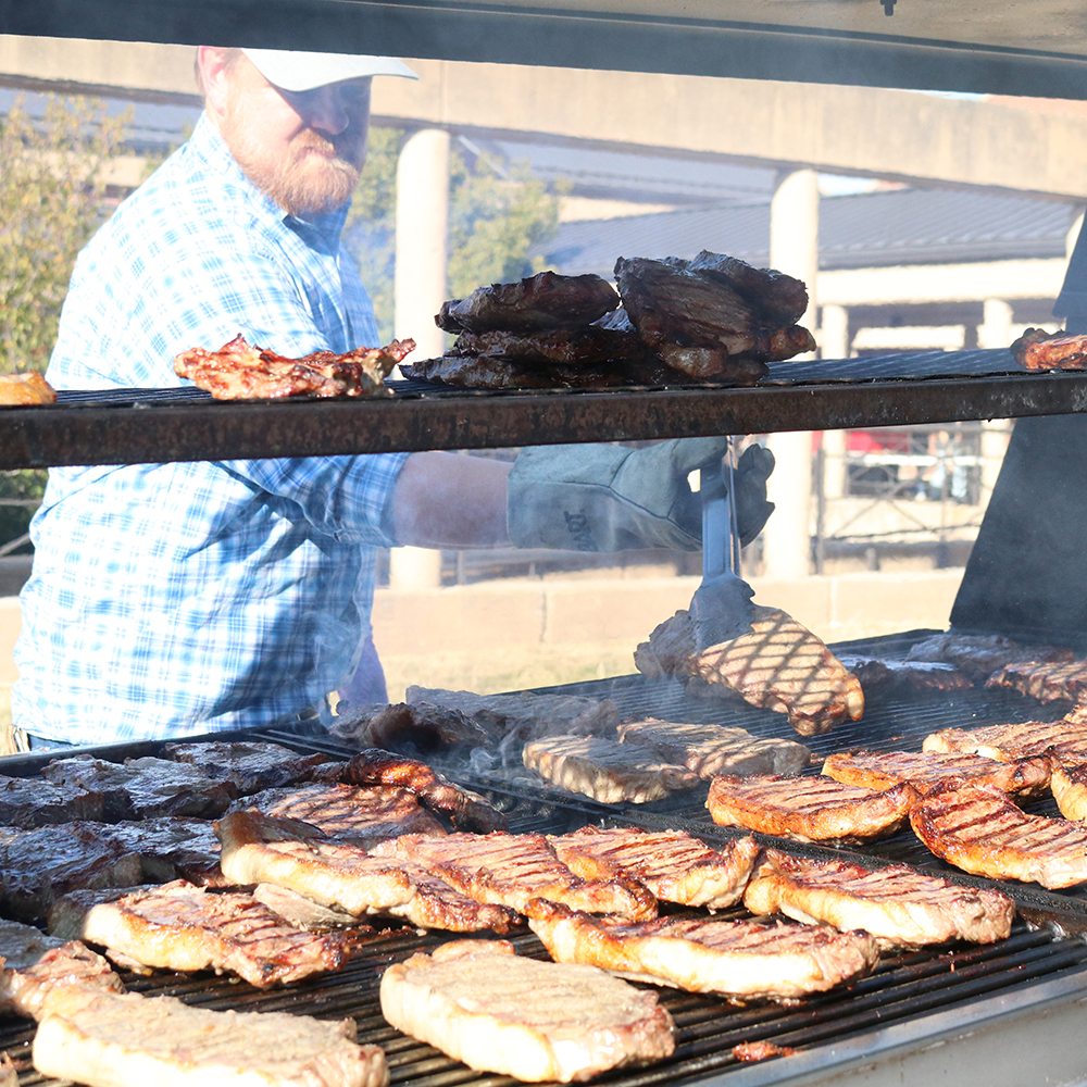 Faculty member Benny Mote helps prepare steaks at the 2022 Block and Bridle Steak Fry