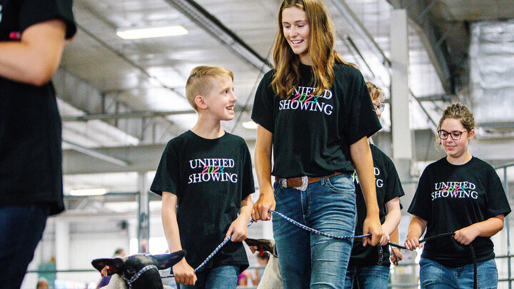 Josh Layman, showman, (left), leads his lamb as a member of the Unified Showing 4-H Club, accompanied by buddy Tatum Terwilliger, a first-year biological systems engineering major. Josh, one of the first members of the club, has honed his skills over the years and this summer was the lightweight champion in the sheep show at the Lancaster County Fair.