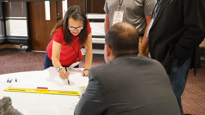 Jennifer Clarke writes on a large piece of paper as three men watch.